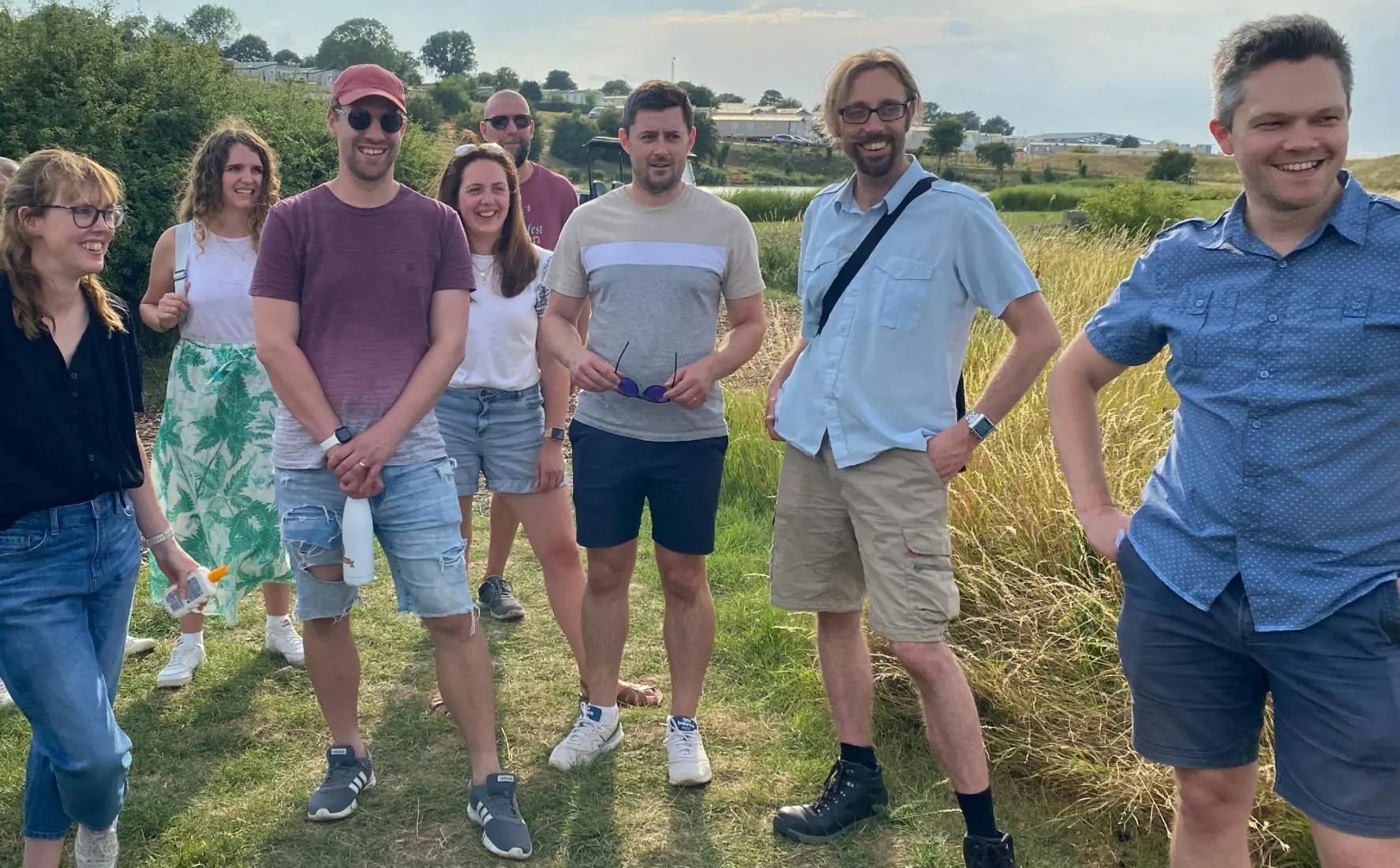 A group of friends standing in a grassy field during a sunny day.