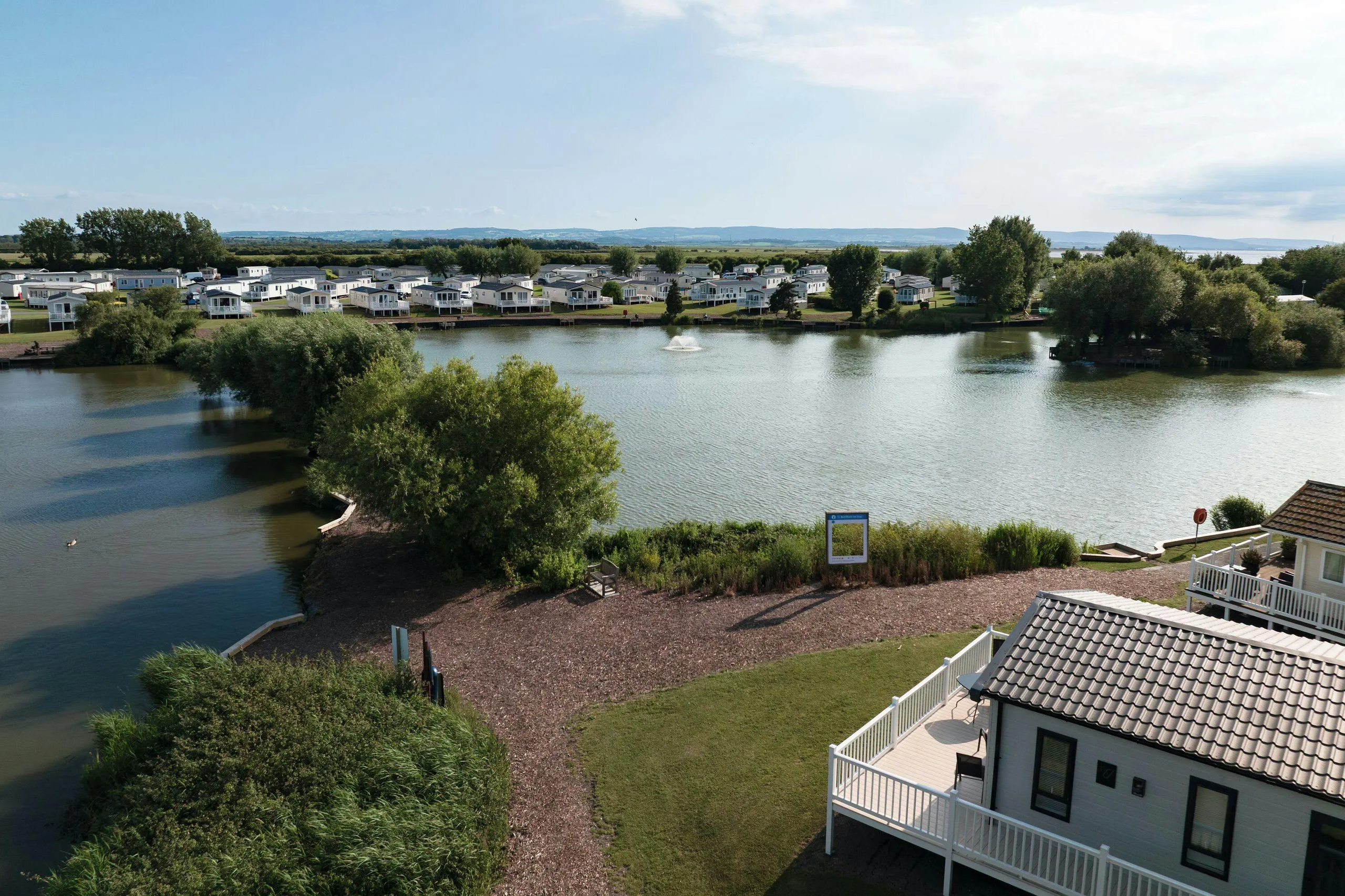 Aerial view of a caravan holiday park featuring rows of mobile homes surrounding a scenic lake.