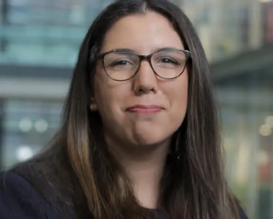 Portrait of Elisha Mann wearing glasses and smiling gently.