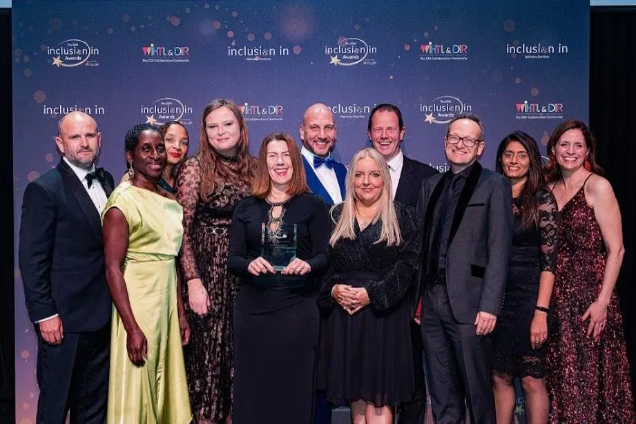 Ten people posing together at the Inclusion Awards event in front of a branded backdrop.