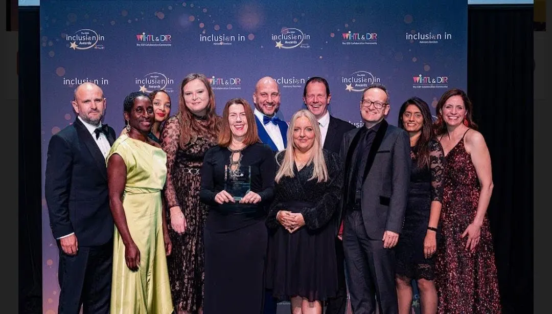 Ten people posing together at the Inclusion Awards event in front of a branded backdrop.