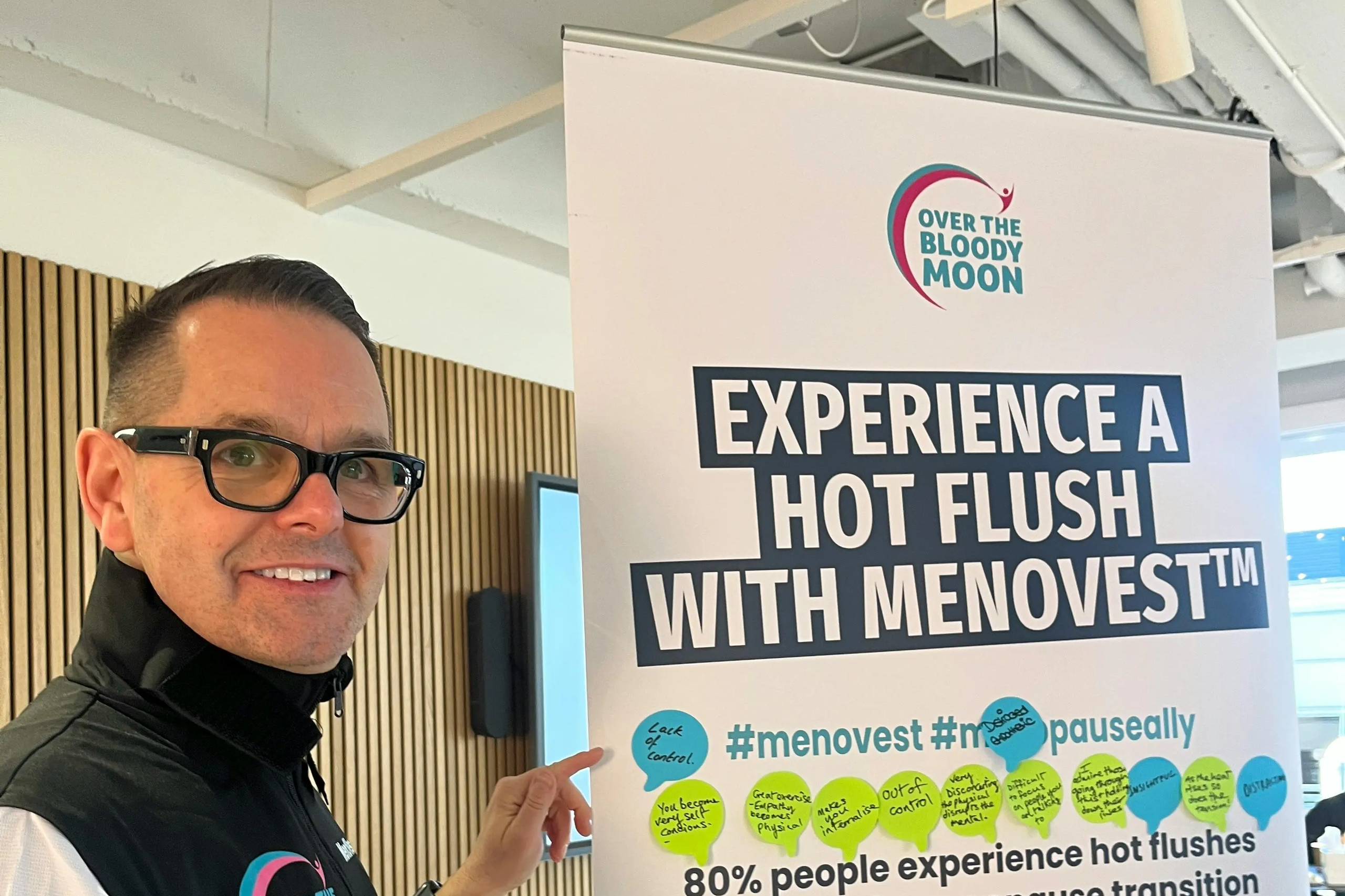 A man pointing at a banner promoting Menovest for hot flushes during menopause.