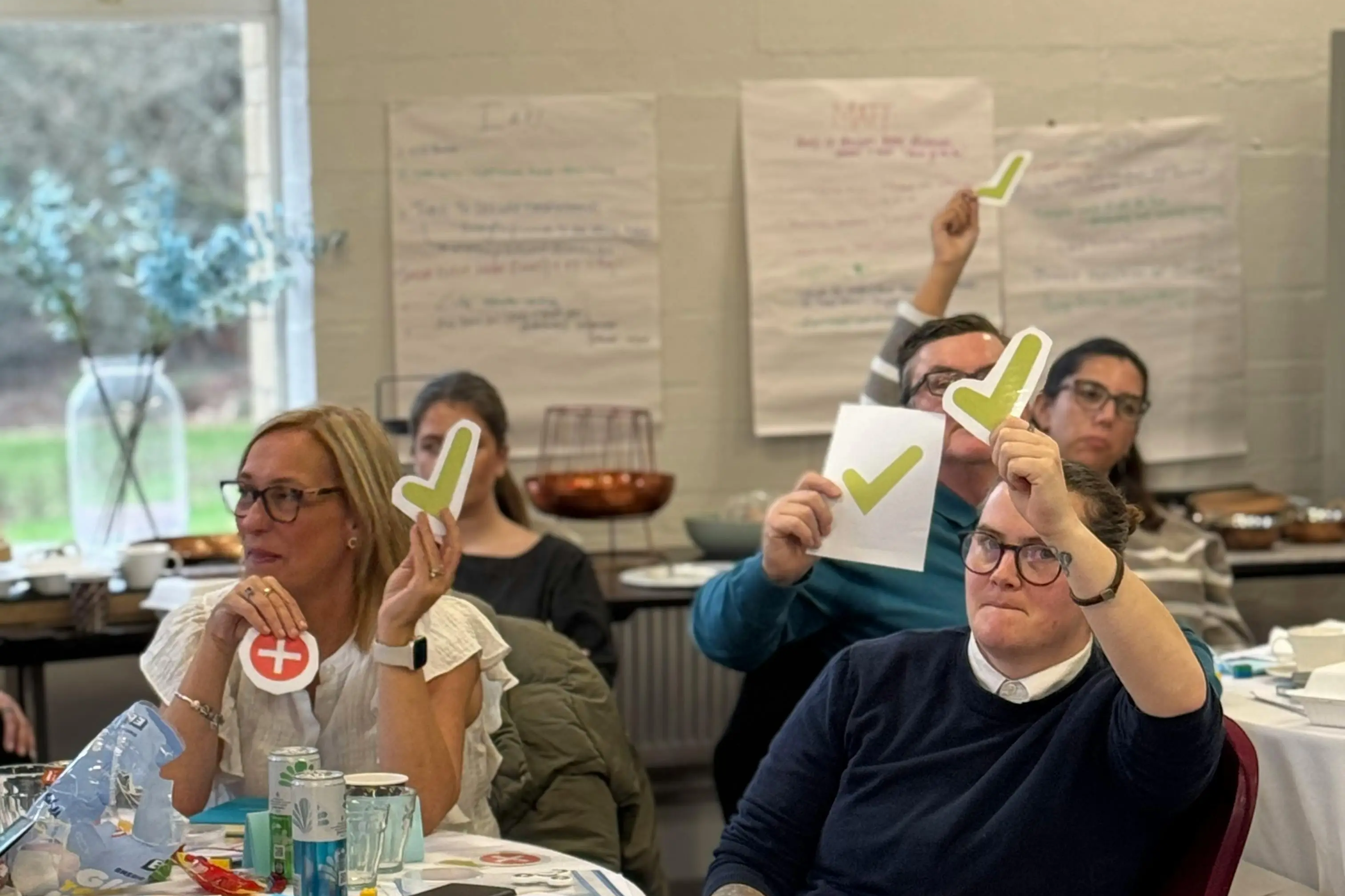Participants at a workshop holding up paper checkmark and cross symbols to vote.