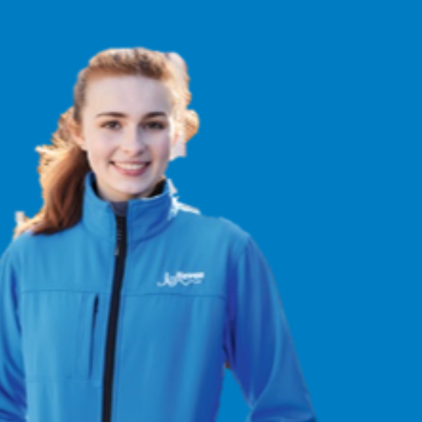 A smiling young woman with brown hair wearing a bright blue jacket against a solid blue background.
