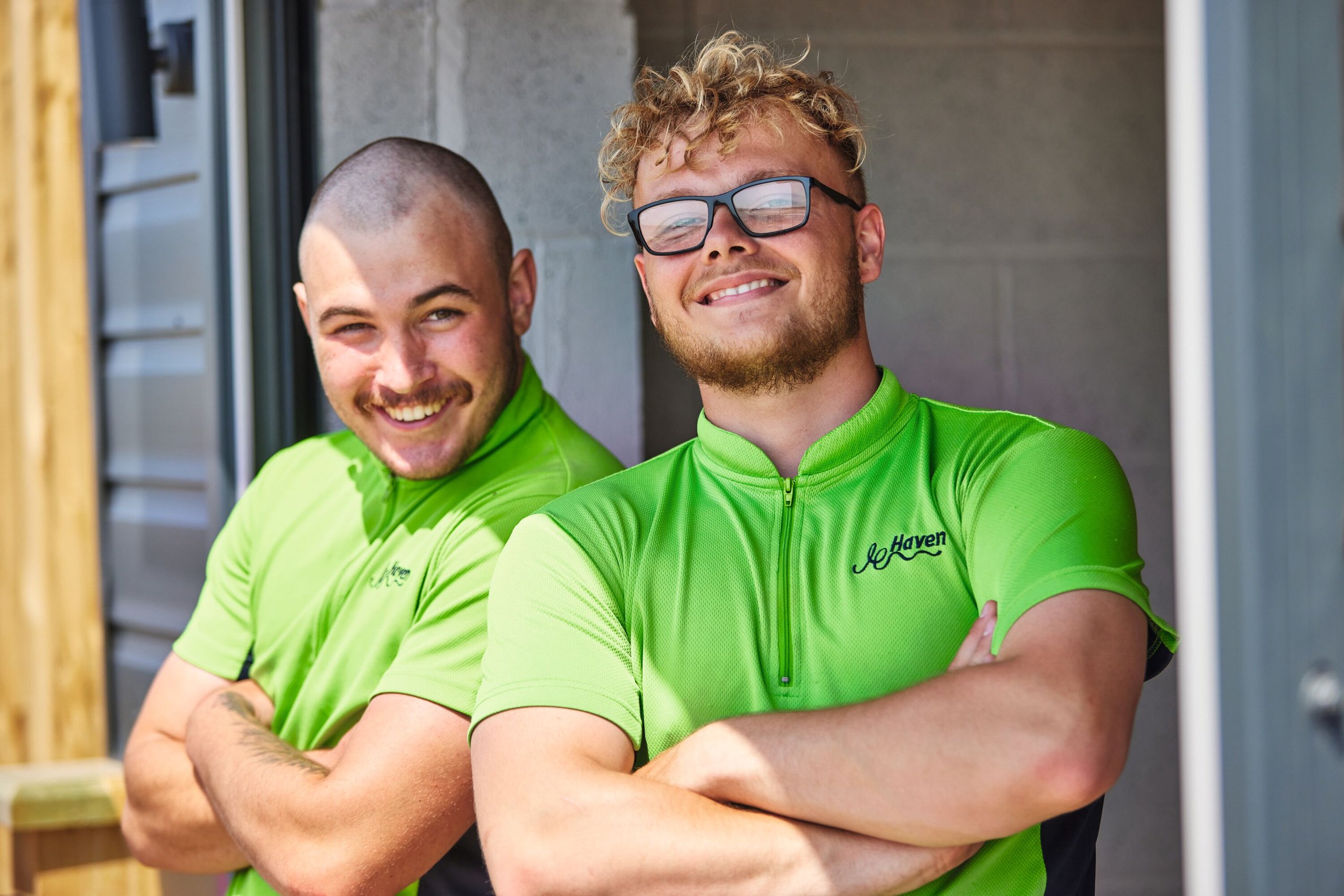 Two smiling men in matching green Haven shirts with their arms crossed.
